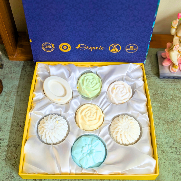 A gift set of seven handcrafted natural chakra healing soaps in various colors, displayed in a yellow box with a blue lid, labeled with 'Organic' and 'Premium' tags.