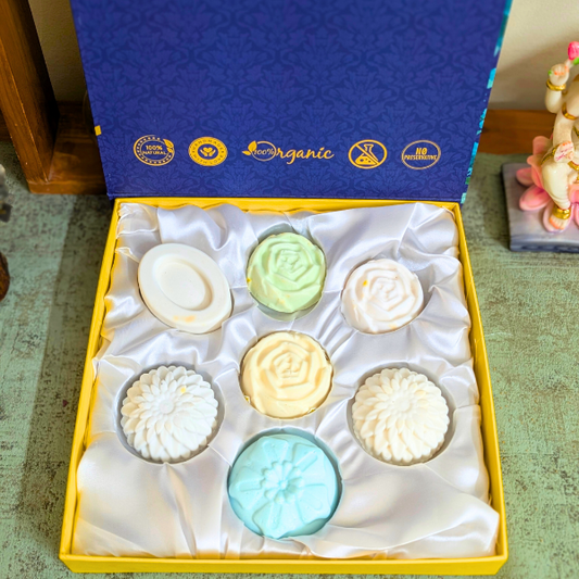 A gift set of seven handcrafted natural chakra healing soaps in various colors, displayed in a yellow box with a blue lid, labeled with 'Organic' and 'Premium' tags.