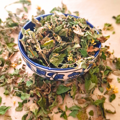Bowl of dried kasuri methi herbs on a bed of green leaves