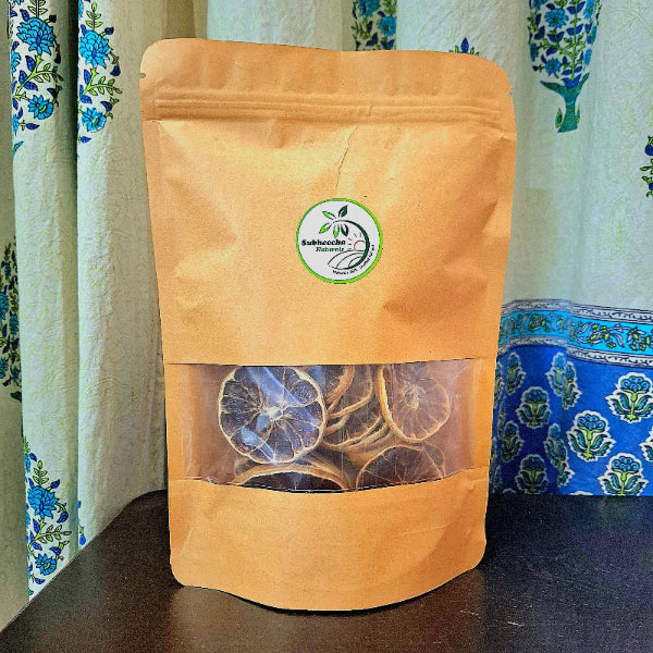 Brown paper bag with transparent window displaying dried lemon slices, against a patterned curtain background.