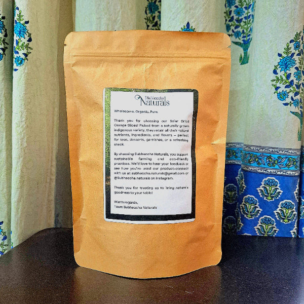 A brown paper orange bag with a label on a wooden surface with a floral-patterned curtain in the background